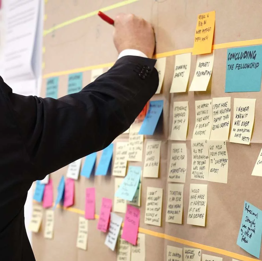 Man organizes tasks on post-its on a bulletin board