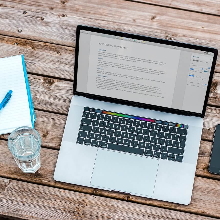 Laptop and a glass of water on a wooden desk