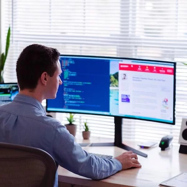 Man sitting in front of two big screens