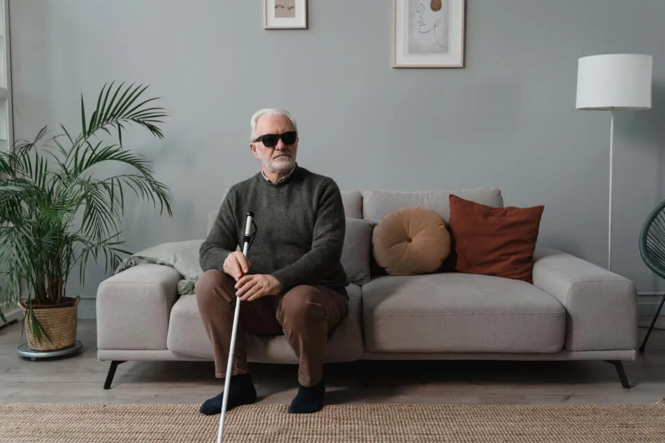 Ein Sehbeeinträchtigter ältere mann sitzt auf dem Sofa