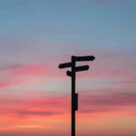 Roter Abendhimmel mit der Silhouette eines Wegweisers