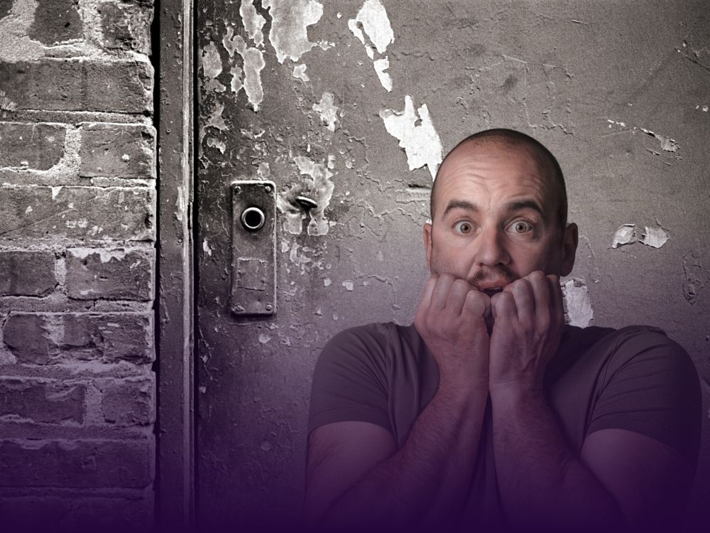 A frightened man biting his nails stands in front of a dilapidated door with no handle, illustrating the frustration of encountering a popup modal without a close button.